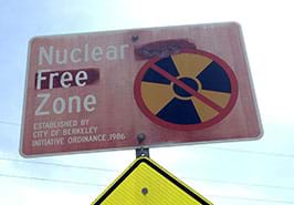 A photograph shows a metal roadway sign that says: Nuclear Free Zone. Established by City of Berkeley initiative ordinance 1986.
