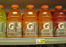 Photo shows five 32-ounce (846 ml) jugs of yellow, orange and red Gatorade sports drink on a grocery shelf. 