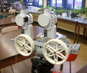 A photograph shows the LEGO MINDSTORMS NXT pulley and gear system used in this activity, mounted on a tripod in a classroom.