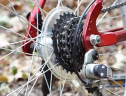 A photograph of the hub of the center of a back bicycle wheel shows the rear gears—a stack of six toothed wheels (sprockets), each with a different number of teeth.