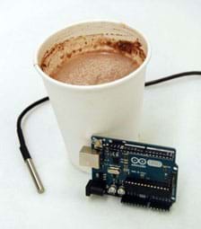 A photograph shows a cup of hot chocolate with an Arduino (microcontroller circuit board) and DS18B20 thermal sensor (long black wire with silver metal probe end) nearby.