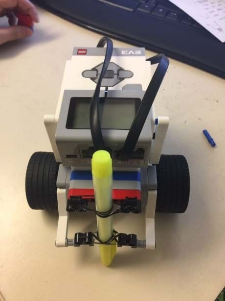 Photo shows a small robot on wheels with a pen secured with rubber bands.