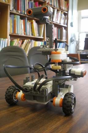 Photo shows a small wheeled robot on a table top.