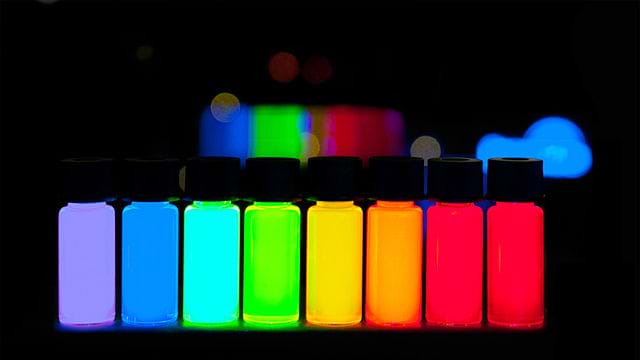 A photograph shows small tubes of manufactured quantum dots of vivid colors ranging from violet to deep red. 
