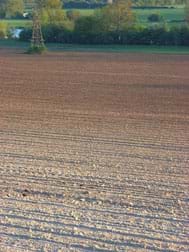 A photograph shows acres of exposed soil prepared for agricultural purposes.