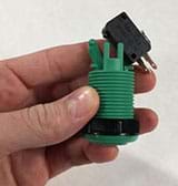 A photograph shows a hand holding a threaded/grooved green and black plastic device (same as in Figure 3; an upside-down arcade button) with a black rectangular switch removed from it.