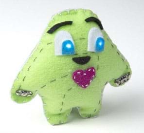 A photograph shows a plump, blob-shaped “plush” toy creature with loosely shaped arms and legs, light-up cartoon eyes (from sewn-in circuit with LEDs), eyebrows and a red heart made of stitched green felt.