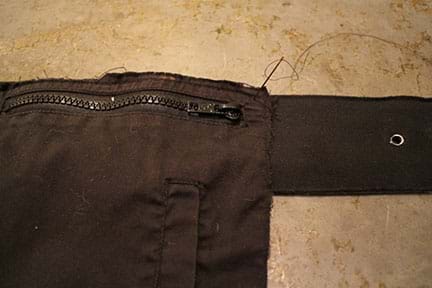A photograph shows a needle and thread being used to sew the top of a zippered black fabric jacket pocket so it hangs from a belt.