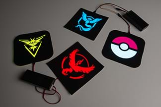 A photograph shows four Pokémon character patches: yellow Zapdos, blue Articuno, red Moltress, and white/pink poke ball. Two patches are each connected to a battery pack.