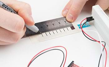 A photograph shows hands holding a ruler and fine-tipped marker being used to mark 6 mm intervals from the breadboard end of the potentiometer to the far end.