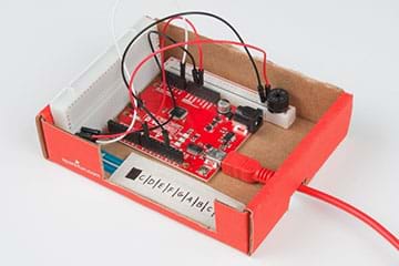 A photograph shows a SparkFun RedBoard attached to breadboards and a potentiometer—all located inside a cardboard box with no lid.