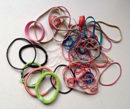 A photograph shows a pile of rubber bands of different colors, sizes, widths and materials, including elastic hair ties.