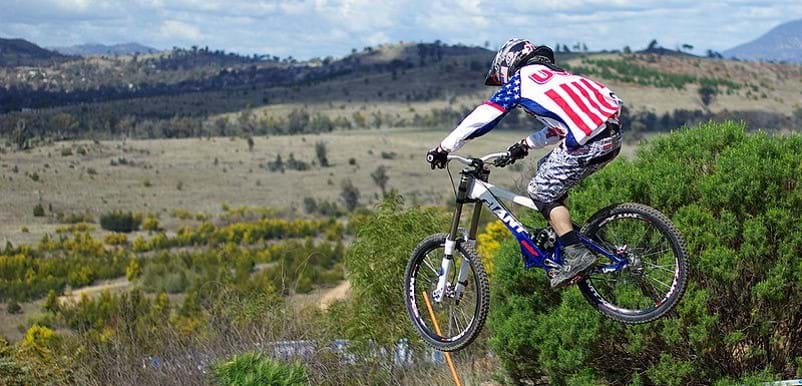 A picture of a person wearing a red, white, and blue shirt midair on a bike. 