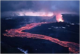 Photo shows a meandering stream of pink and yellow lava flowing down a hillside from a steaming volcano vent.