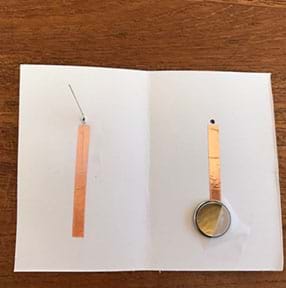 Photograph of the inside of the cardstock element.  The LED’s SHORT wire is taped downed completely to the copper tape on the left side (inside cover).