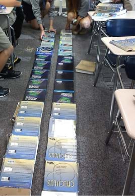 Photo shows a double line of textbooks on a classroom floor, end-to-end, the two tracks ~10 cm apart.
