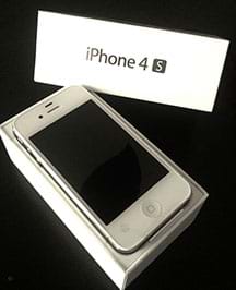A photograph shows a rectangular white Apple iPhone 4s sitting in a white box with the box lid nearby; this is the original product packaging.