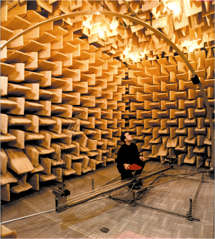 An acoustical engineer measures a sound instrument inside an anechoic chamber.