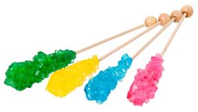 A photograph shows four wooden skewers, each with a cluster of jagged colored crystals at one end: green, yellow, blue and red.