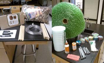 Two photographs: On a table are a package of cardboard interlocking packing pieces, a moving glass divider kit, a coiled length of clear vinyl tubing, a handful of 16-inch wooden dowels, a handful of wooden flat sticks, two 4-inch and two 6-inch pieces of black PVC pipe. On the barter table are roll of bubble wrap, roll of white plastic packing foam, bottle of wood glue, roll of orange polypro twine, six rolls of patterned/colored duct tape, roll of silver duct tape, package of white plastic zip ties, four 8-inch and four 5-inch silver screw bolts, along with a stack of paper vouchers.