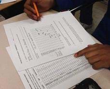 Photo shows a student at a table plotting points on a graph from data listed on a second sheet.