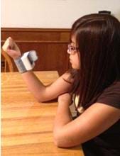 Photo shows a girl looking at a device strapped to her wrist.
