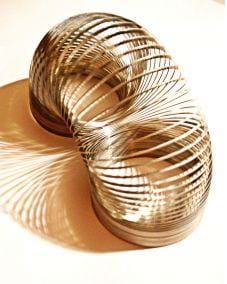 A photograph shows a metal slinky, arched to show its composition.