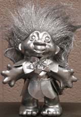Photo shows a bronzed-looking, standing troll doll with big hair.