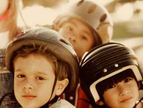 Photo shows three young children wearing helmets.