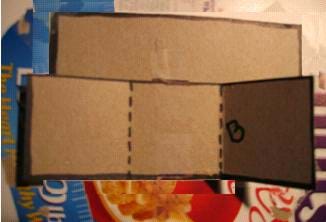 Photo shows the long folded cardboard piece attached to the back of rectangle A cardboard piece.
