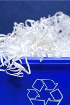 Photograph of a blue recycling bin overflowing with shredded paper.