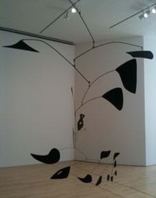 A photograph of a Calder mobile at the SF MOMA - a balance of black wires and random black shapes.