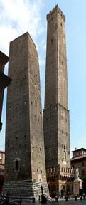 Photograph shows two-side-by-side masonry towers in Bologna, Italy. One is ~300 feet high and the other is ~150 feet high.