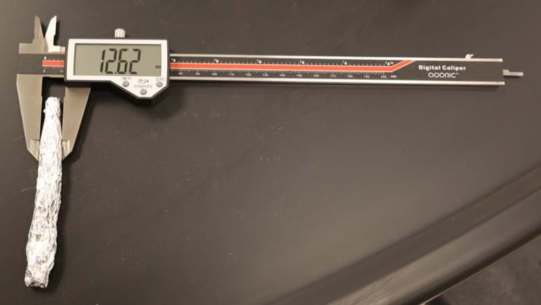 A photo showing aluminum foil that has been wrapped up into a cylinder, with calipers being used to measure the diameter. A photo showing aluminum foil that has been wrapped up into a cylinder, with calipers being used to measure the diameter.
