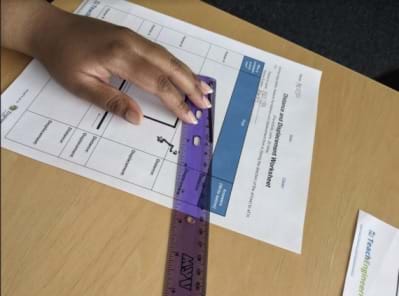 A student is measuring distance on the worksheet.