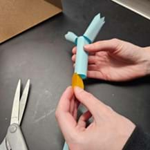 A photo showing a student attaching the goldenrod paper or pH paper to create the model of the enzyme-linked/conjugated secondary antibody.