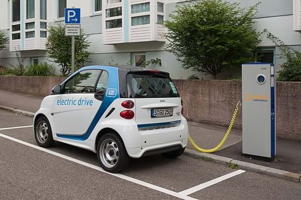 An electric vehicle parked and plugged into a roadway charger.