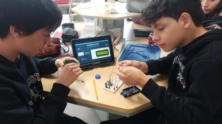 A photo showing two students working collaboratively to construct an Arduino air quality monitor.