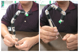 Side-by-side photos of a person demonstrating a functioning model finger, with the finger relaxed on the left and flexed through string tension on the right. Side-by-side photos of a person demonstrating a functioning model finger, with the finger relaxed on the left and flexed through string tension on the right.