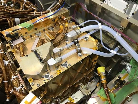A photo showing a close-up view of the MOXIE instrument’s internal components, including gold-colored metal panels, silver fittings, and multiple translucent tubes connected to valves and ports. A photo showing a close-up view of the MOXIE instrument’s internal components, including gold-colored metal panels, silver fittings, and multiple translucent tubes connected to valves and ports.