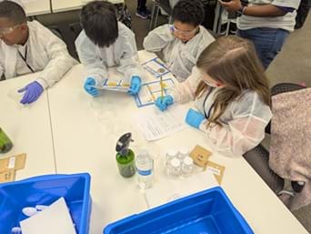 A photo of four students wearing personal protective equipment working on their project. A photo of four students wearing personal protective equipment working on their project.