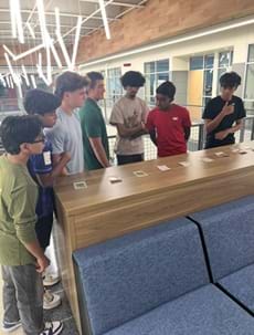 A photo showing seven students standing near a counter looking at the categories of 12 Ethics Twist Cards. A photo showing seven students standing near a counter looking at the categories of 12 Ethics Twist Cards.