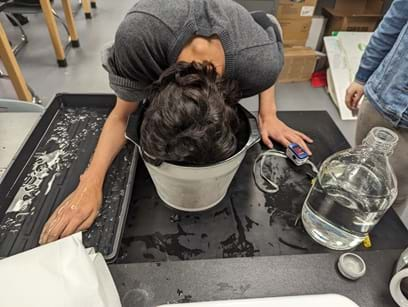 A photo of a student dunking their face into ice water during a simulated panic attack while measuring heart rate. 