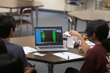 A photo showing students working in a group recording and observing EMG data on their computer in class. A photo showing students working in a group recording and observing EMG data on their computer in class.