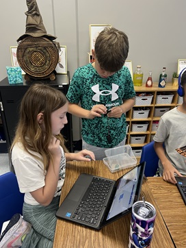 A photo showing two students working together to code their micro:bits to show how the eye sees an image and then the retina signals the inverse to the brain. 