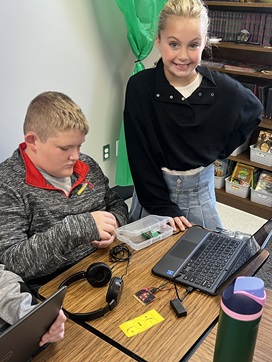 A photo showing two students working together to create a program that simulates light intensity.