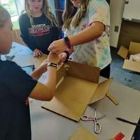 A photo of students building a box that will hold a device to water the cups.