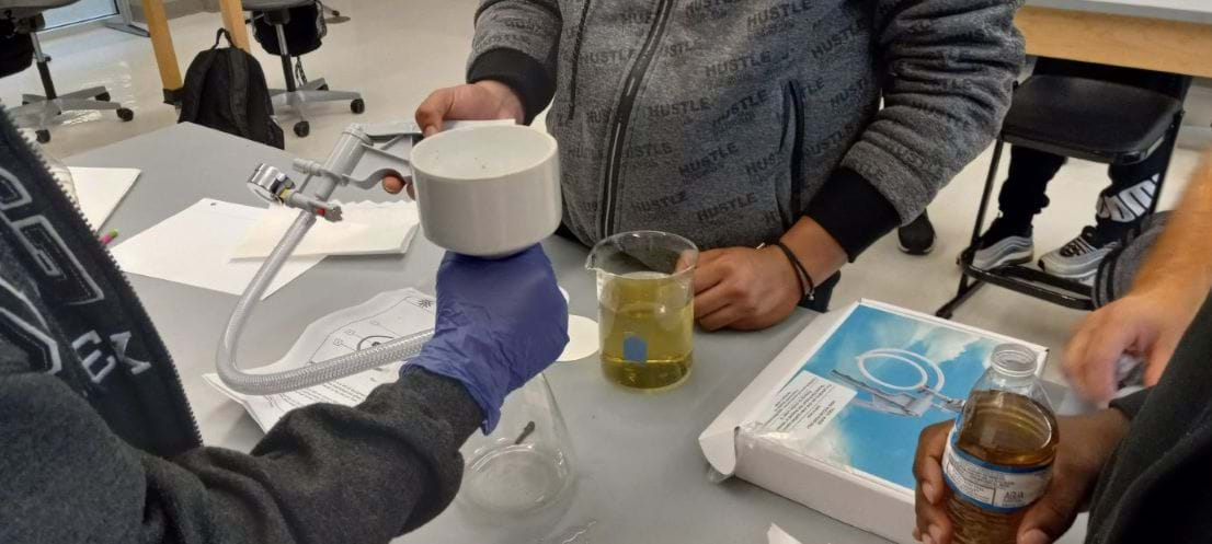 Photo showing three students using a filtering flask to filter water with algae present.