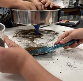 A photo showing students gathering their separated potting soil with a trowel.