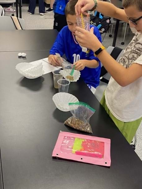 A photo showing students building water filtration systems. 